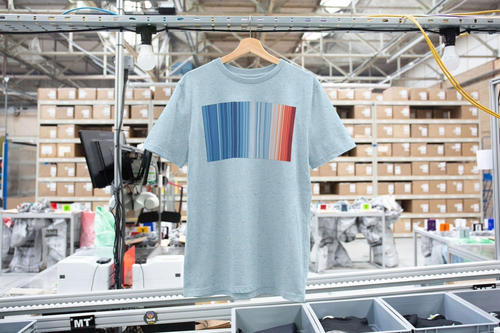 A #ShowYourStripes t-shirt hanging on a rail in a t-shirt print facility